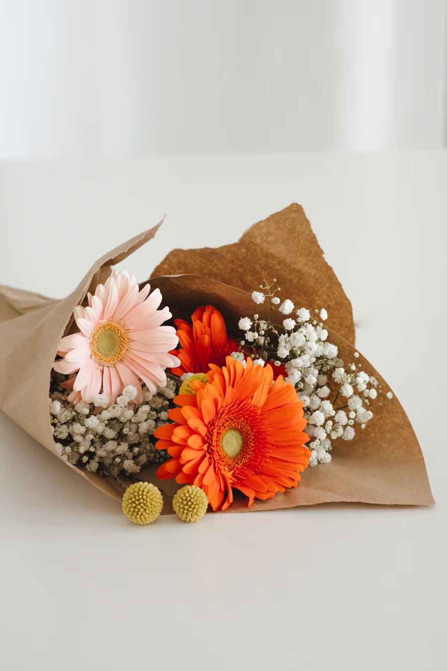 Petite composition kraft avec gerberas rose et orange, gypsophile, craspedias jaunes